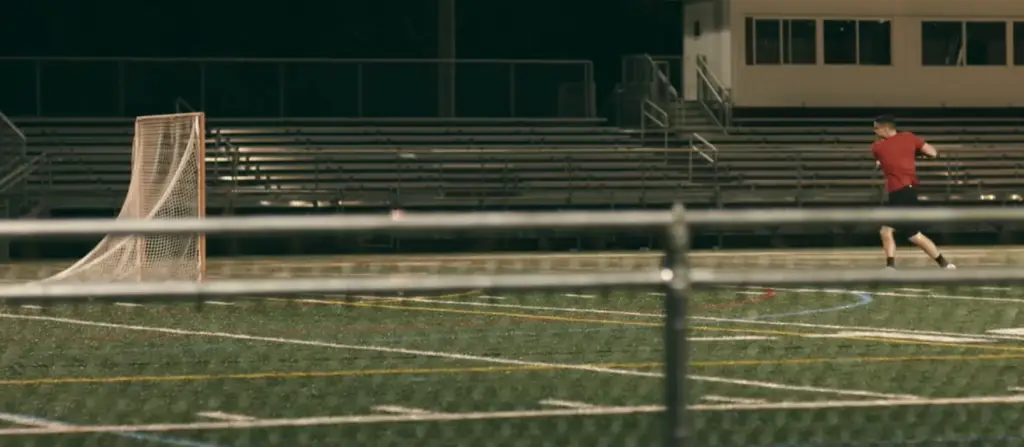 A man is playing lacrosse on a field at night with an AXON2.